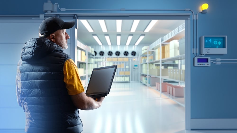 Man,Storekeeper,With,Laptop.,Refrigerated,Warehouse.,Large,Freezer,In,Factory.